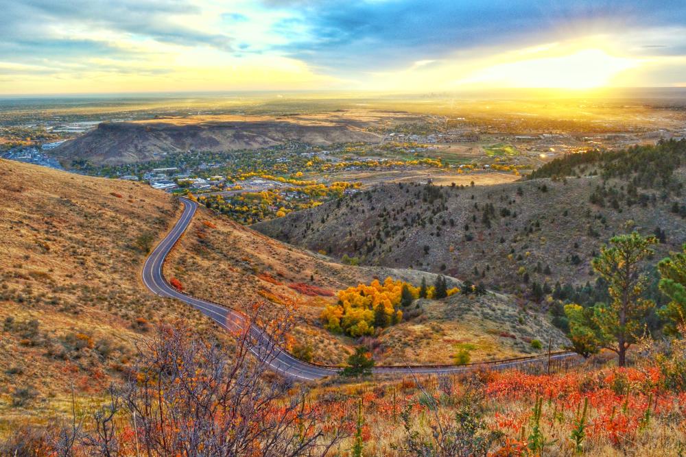 Golden, Colorado, at sunrise, seen from Lookout Mountain Road, with vibrant fall colors of yellow and orange in the foreground.