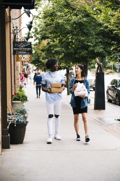 A couple with food take out bags and boxes walking along Washington Ave. in downtown Golden Colorado.